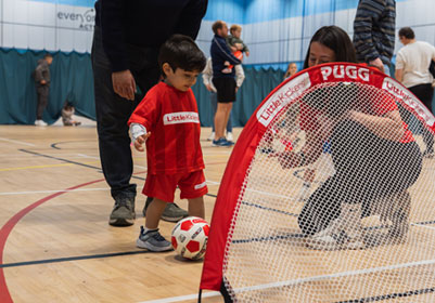 Toddler boy in Little Kickers kit playing football