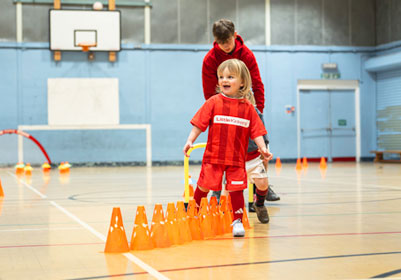 Child player in Little Kickers kit practicing skill
