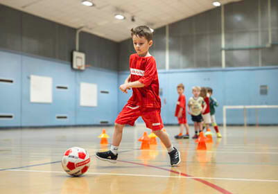 Young child in Little Kickers kit playing football