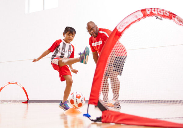 a person and child kicking a football ball